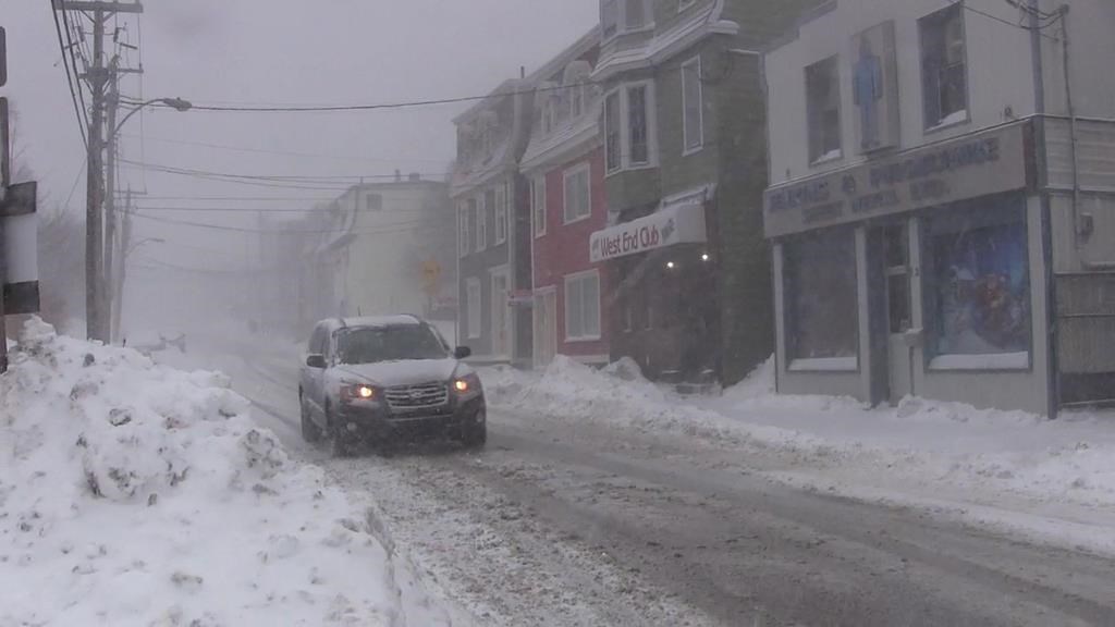 A car drives downs a snow-covered street in St. John's on Wednesday, Jan. 2, 2019.
