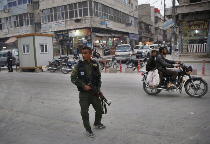 In this file photo taken on Wednesday, March 28, 2018, a member of the Kurdish internal security forces patrols a commercial street in Manbij, north Syria.