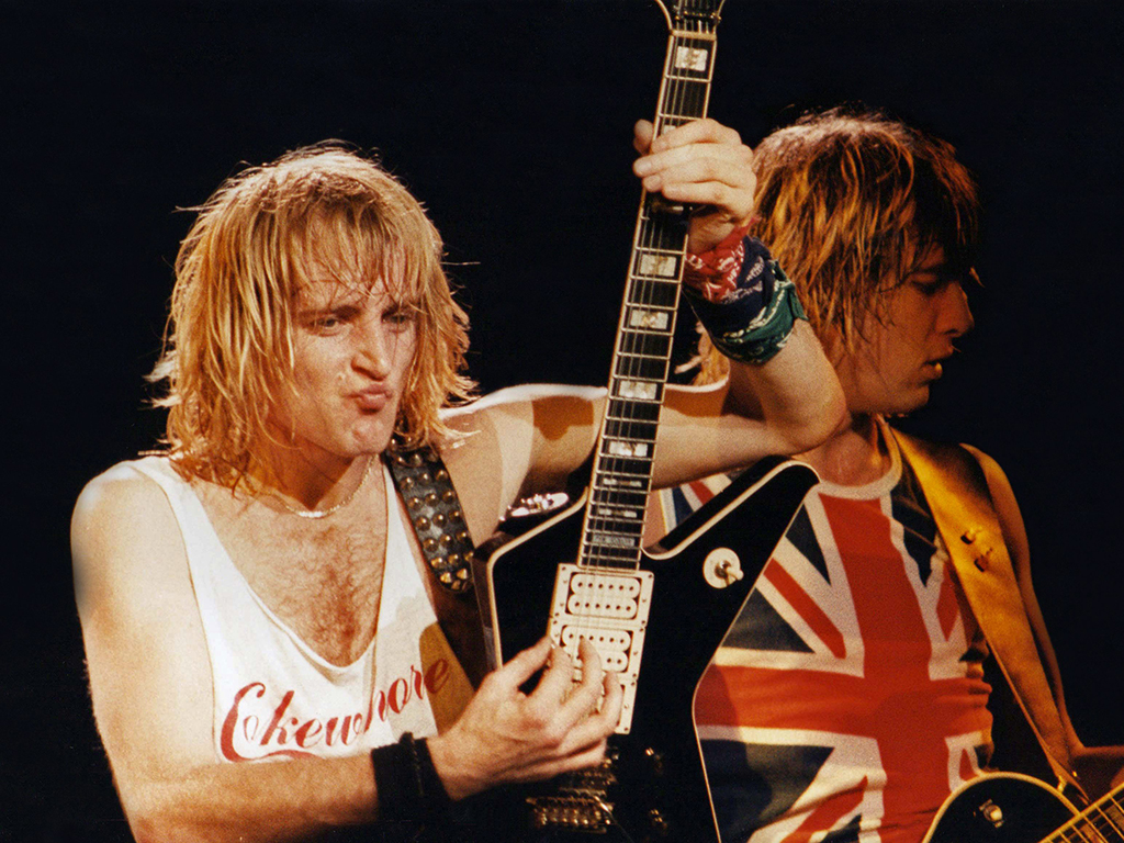 (L-R) Phil Collen and Joe Elliott of Def Leppard perform on stage at Hammersmith Odeon on Dec. 5, 1983 in London, England.
