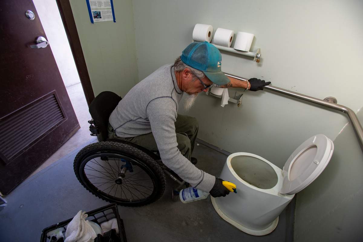 Wheelchair-bound Rand Abbott, 55, of Joshua Tree cleans a bathroom stall by himself in Joshua Tree National Park on Jan. 8, 2019, in Joshua Tree, California.