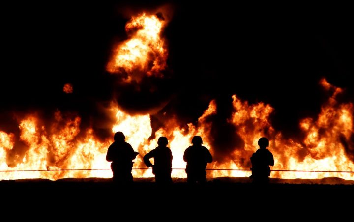 Soldiers stand guard in front of a wall of fire after an explosion of an illegal tap on Mexican oil company Pemex’s pipeline in Tlahuilipan, Hidalgo, Mexico, late at night on Jan. 18, 2019.