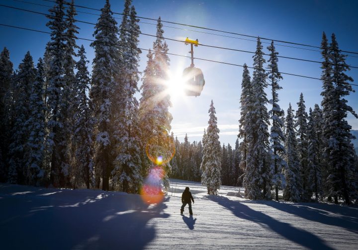 A snowboarder passes under a gondola on a cold but sunny day at a ski resort in Lake Louise, Alta., Saturday, Nov. 29, 2014.