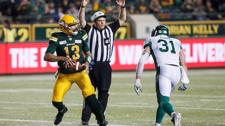 Edmonton Eskimos' Mike Reilly (13) scores a touchdown as Saskatchewan Roughriders' Sam Hurl (31) reacts during second half CFL action in Edmonton on Thursday, Aug. 2, 2018. 