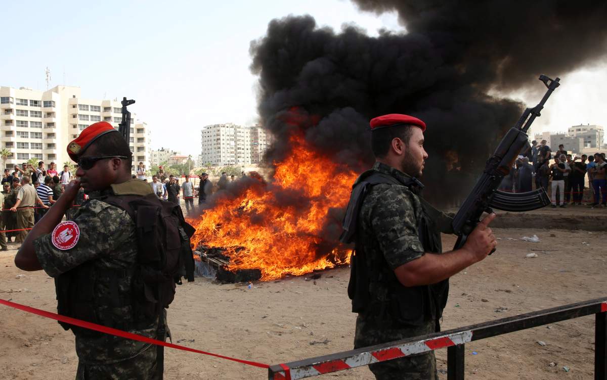 Hamas security forces stand guard while they burn some 1,383 bars of hashish and 1,242,000 pills of Tramadol, that have been seized since the beginning of the year, before they burn it, in Gaza City, Monday, Oct. 22, 2018. (