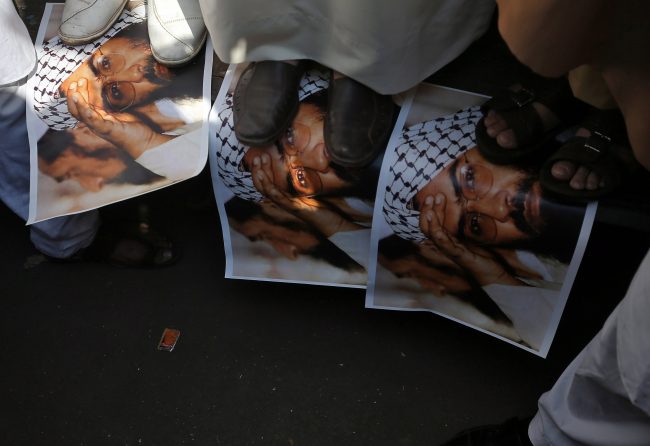 Demonstrators step on the posters of Maulana Masood Azhar, head of Pakistan-based militant group Jaish-e-Mohammad, during a protest in Mumbai, India, Feb. 15, 2019.