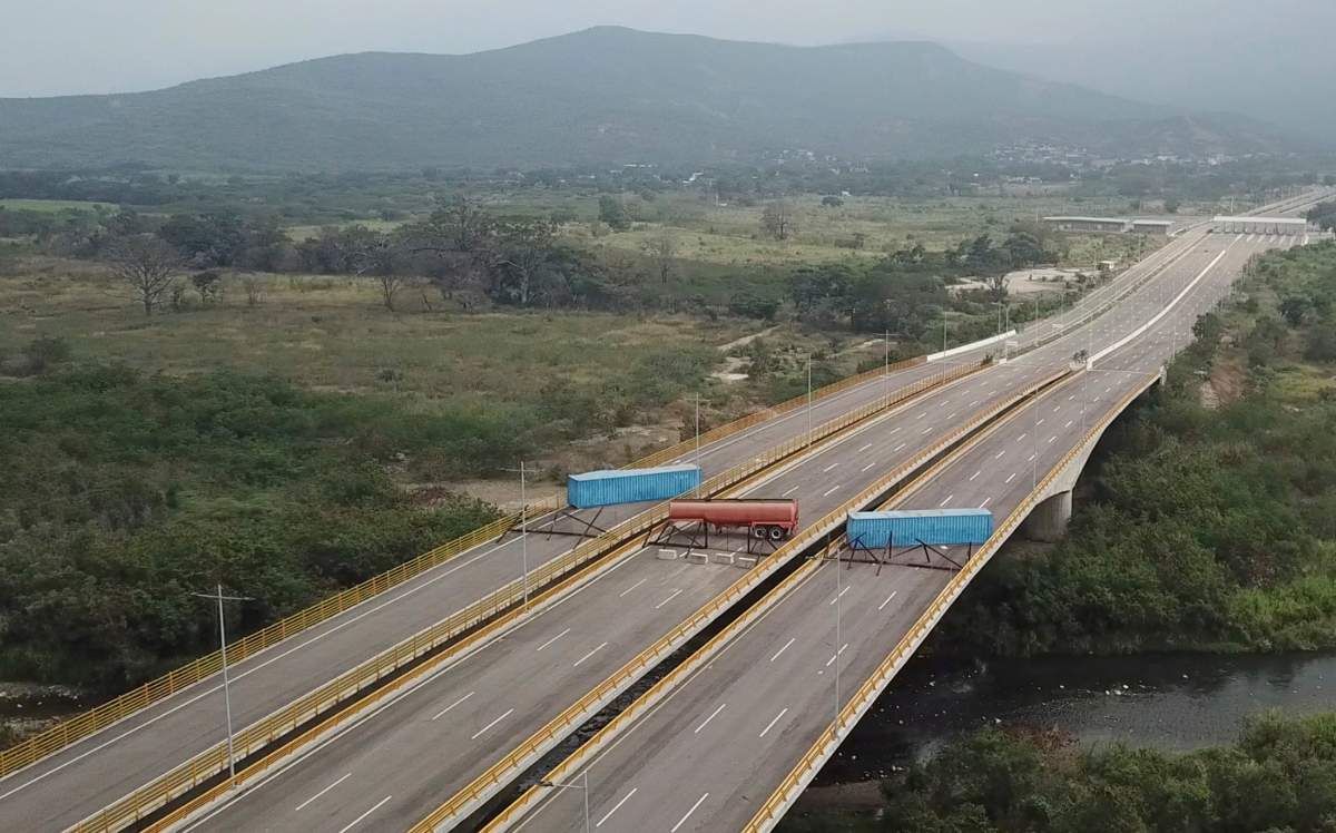 This image taken from video, shows a fuel tanker, cargo trailers and makeshift fencing, blocking the Tienditas International Bridge in an attempt to stop humanitarian aid entering from Colombia, as seen from the outskirts of Cucuta, on Colombia’s border with Venezuela, Wednesday, Feb. 6, 2019. Immigration authorities say the Venezuelan National Guard built the roadblock a day earlier.