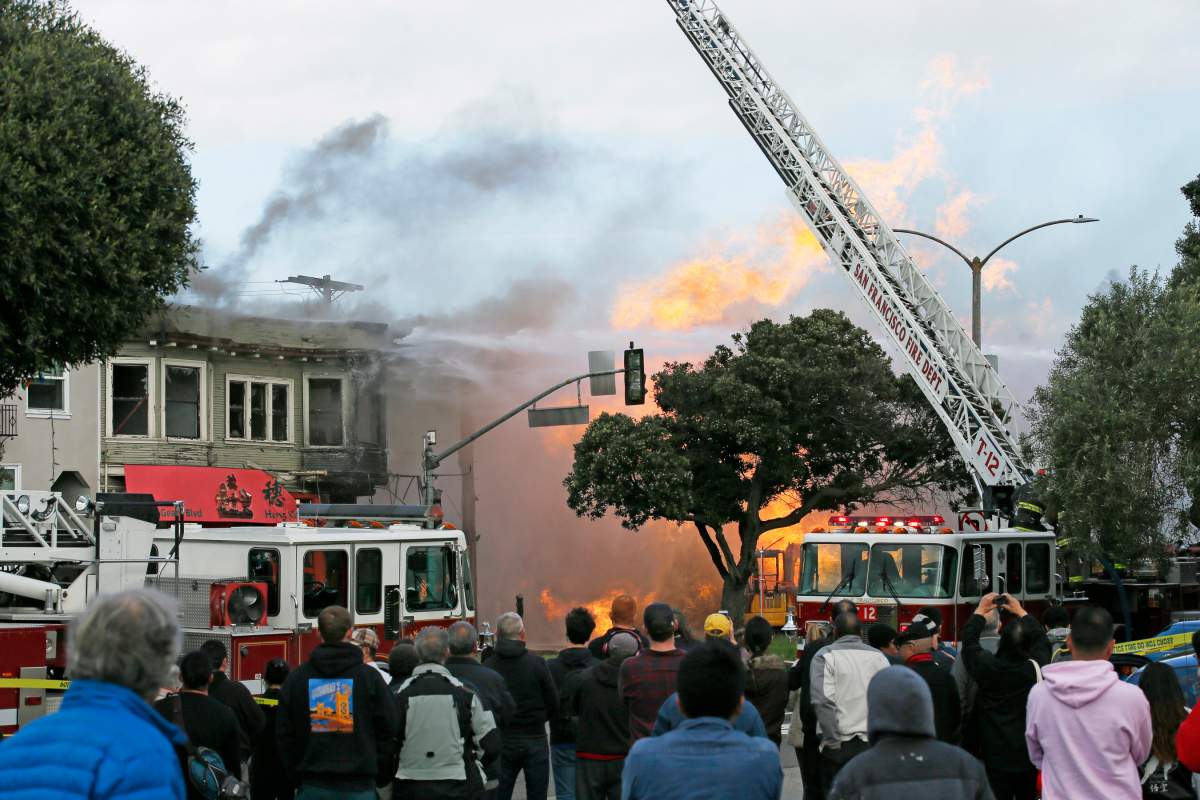 People watch as firefighters battle a fire following an explosion Wednesday, Feb. 6, 2019, in San Francisco, Calif.