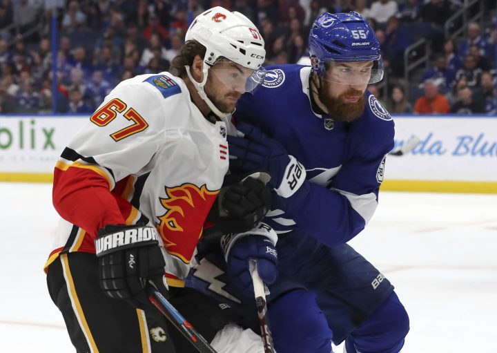 Calgary Flames’ Michael Frolik, left, of the Czech Republic, goes into the boards for a loose puck against Tampa Bay Lightning’s Braydon Coburn during the first period of an NHL hockey game Tuesday, Feb. 12, 2019, in Tampa, Fla.