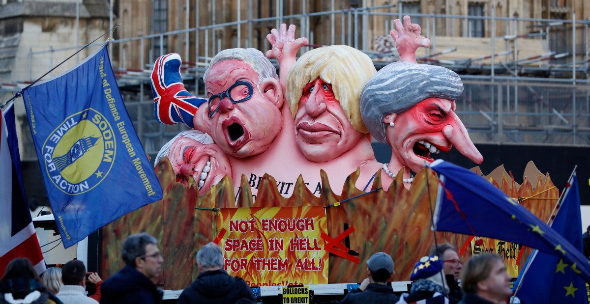 Anti-Brexit demonstrators stand next to a van with large cartoon style portraits of leading British politicians including, from right, Prime Minister Theresa May, Boris Johnson, Michael Gove, David Davis, outside the Palace of Westminster in London, Thursday, Feb. 14, 2019.