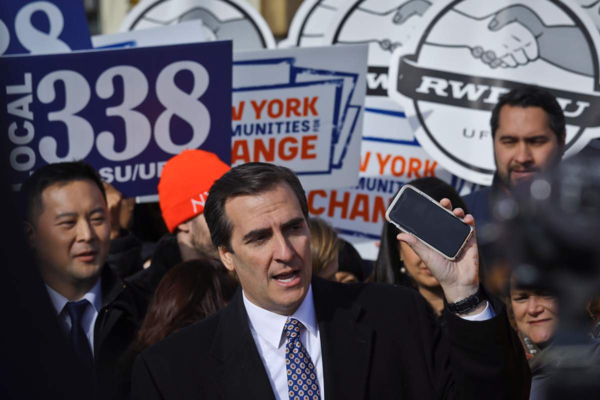 FILE – In this Nov. 14, 2018 file photo, New York State Sen. Michael Gianaris, center, calls on supporters to remove the Amazon app from their phones and boycott the company, as he address a coalition rally and press conference in New York. The first clue that opposition to the project could succeed in derailing the deal came in early February, when Gianaris was appointed to a seat on a state panel that often has to approve state funding for big economic development projects. According to the rules governing the 5-member Public Authorities Control Board, funds for any individual project can be vetoed by a single member, meaning that if the Amazon deal went before the board, Gianaris could kill it unilaterally.