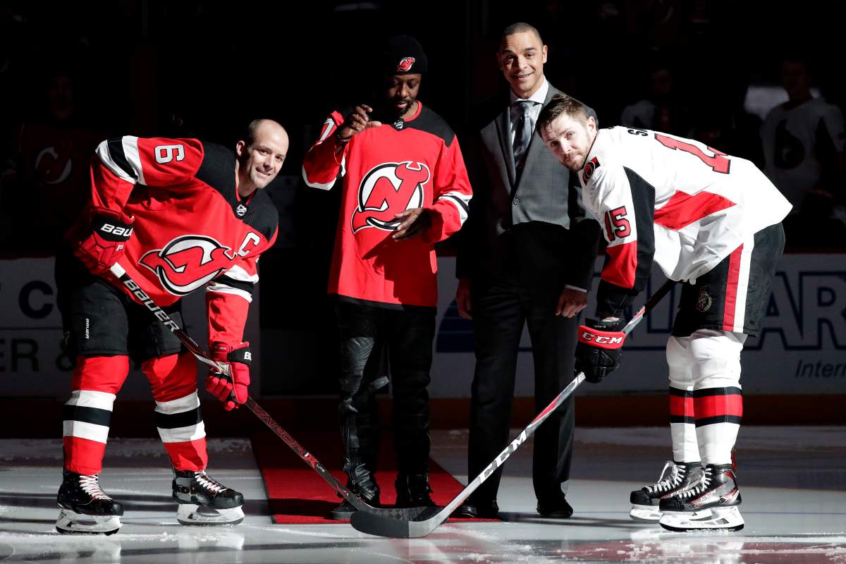 Rapper Wyclef Jean, centre left, stands at centre ice with former New Jersey Devils player Bryce Salvador, centre right, during the ceremonial puck drop with the Devils’ Andy Greene (6) and Ottawa Senators left wing Zack Smith (15) prior to an NHL hockey game, Thursday, Feb. 21, 2019, in Newark, N.J. (AP Photo/Julio Cortez)