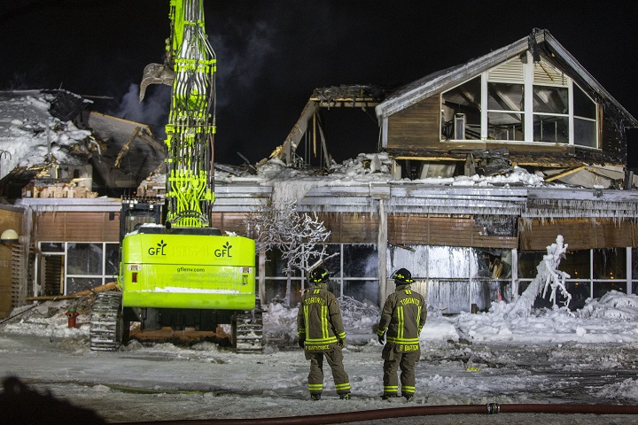 Heavy machinery was brought in Friday night to tear away parts of the roof and expose hot spots.