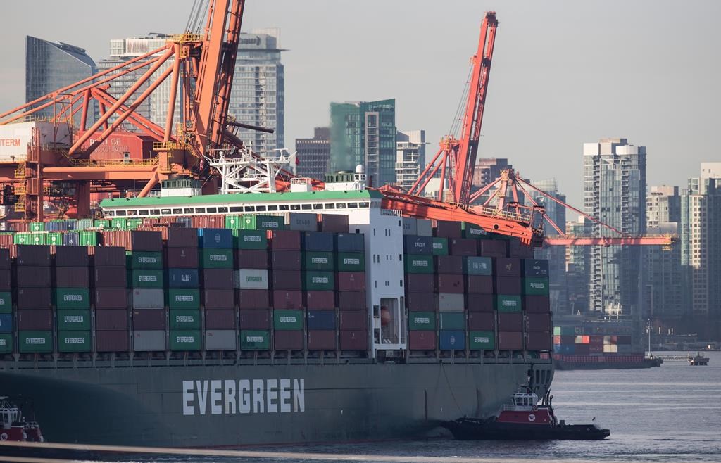 A tugboat is seen near the stern of a freighter after a large crane collapsed on the container ship at Port Metro Vancouver's Vanterm facility, in Vancouver, on Monday January 28, 2019. The container ship that was trapped under a huge collapsed crane in Vancouver harbour has now headed back to sea.