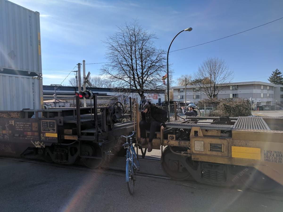 Cyclists climb over an idling train on the Adanac bike path.