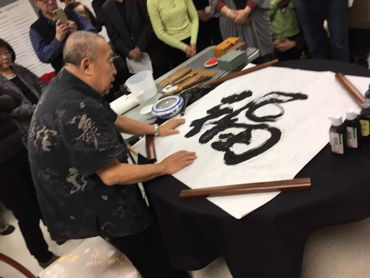 Dr. Steven Aung uses Chinese calligraphy to write the character for “good fortune.”