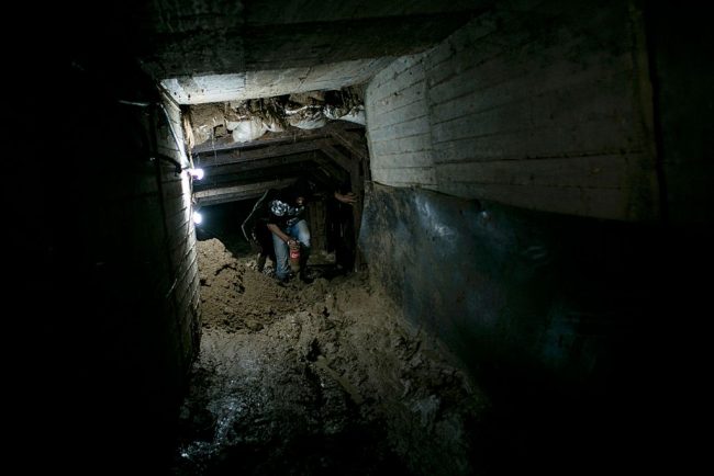 In this March 1, 2016 file photo, Palestinian men walk in the mud at the entrance of a tunnel used for smuggling supplies between Egypt and the Gaza Strip.




