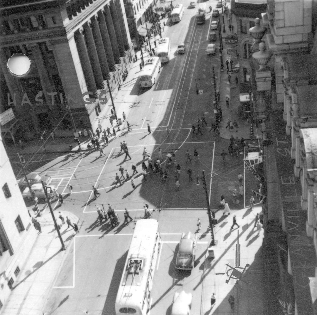 Pedestrians cross diagonally on Granville Street at Hastings in downtown Vancouver, circa 1952.