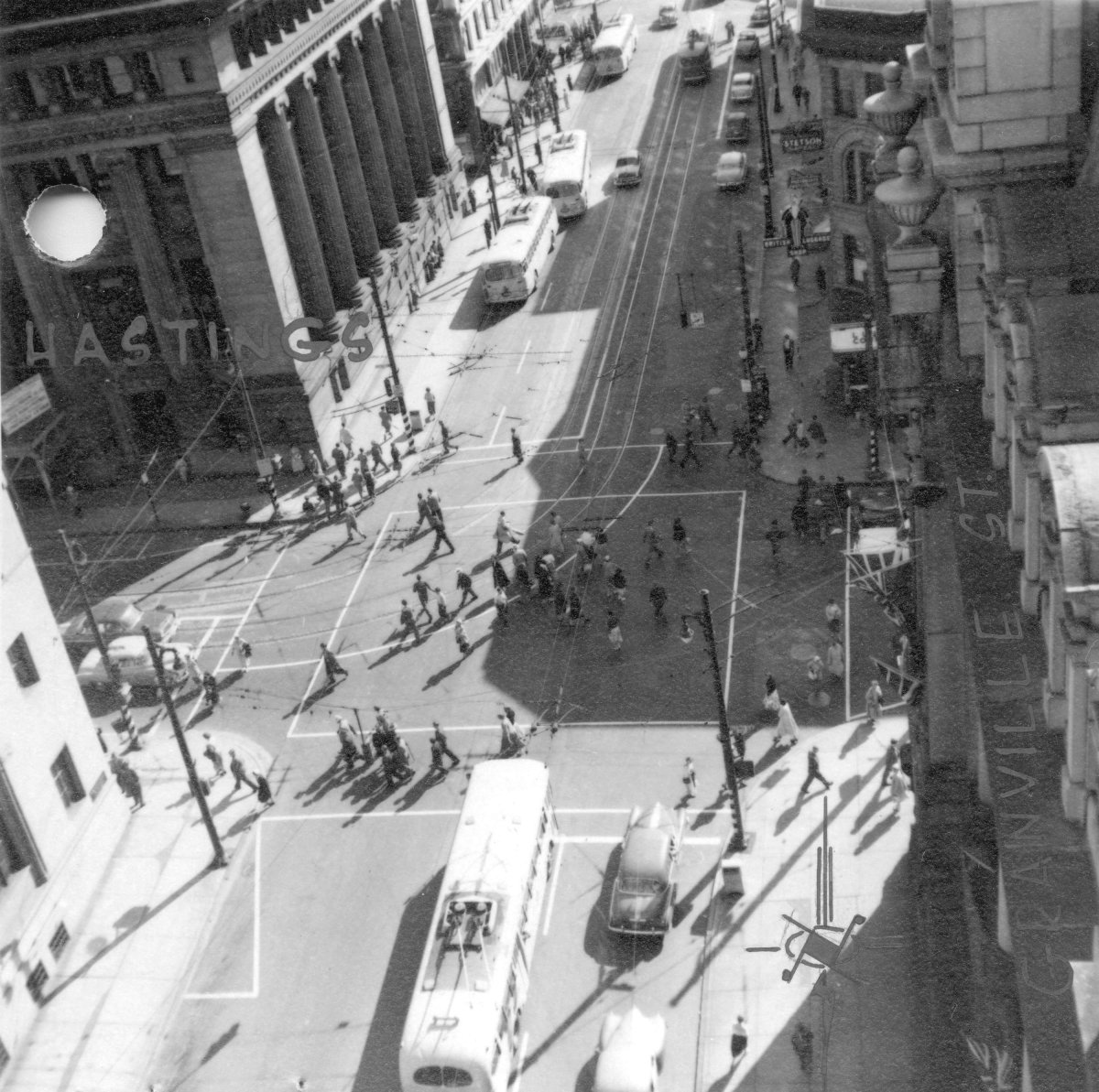 Pedestrians cross diagonally on Granville Street at Hastings in downtown Vancouver, circa 1952.