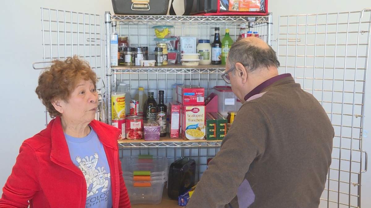 Volunteers examine food in a cabinet at the new meals on wheels kitchen in DDO, set up by Volunteer West Island at the DDO civic Centre.  (Global News).