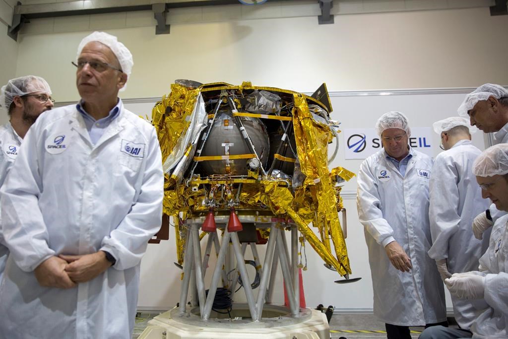 In this Monday, Dec. 17, 2018 file photo, technicians stand next to the SpaceIL lunar module, an unmanned spacecraft, on display in a special clean room during a press tour of their facility near Tel Aviv, Israel.