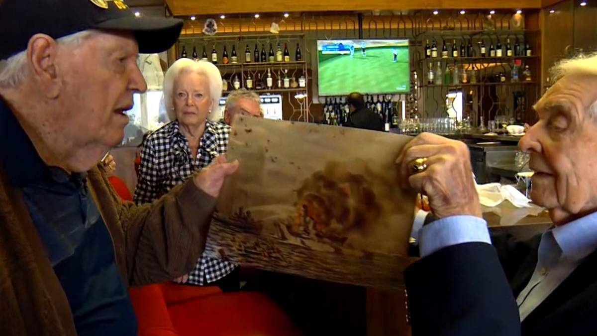 A painting of the U.S.S. Lamson on fire is handed from Bob Apple to fellow veteran Duane Sherman.