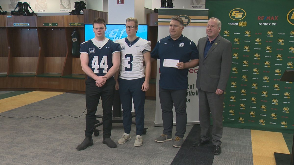 Edmonton Eskimos president and CEO Len Rhodes poses with players and the coach from Edmonton Wildcats Football at a presentation of the Eskimos 50/50 money on Feb. 20, 2019.