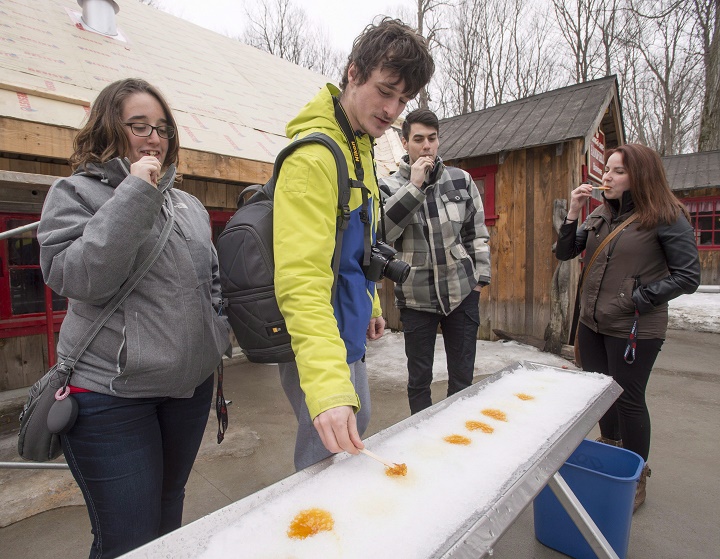 In this file photo, guests at the Domaine Handfield sugar shack sample some hot maple syrup on snow. More and more sugar shacks are offering vegetarian and vegan menus. Saturday, March 10, 2019.