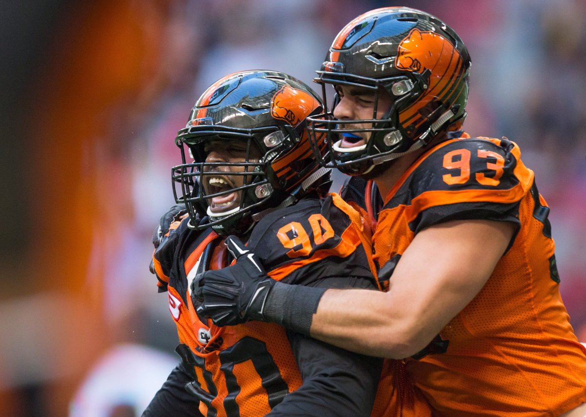 B.C. Lions' Mic'hael Brooks, left, and Craig Roh celebrate after Brooks stopped Calgary Stampeders' quarterback Drew Tate on a third and goal play during the first half of a CFL football game in Vancouver, B.C., on Saturday June 25, 2016. 