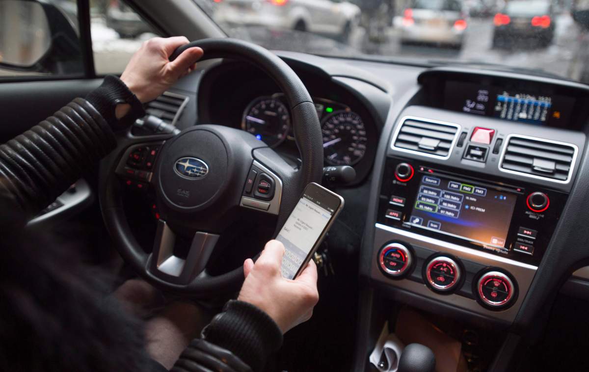 A driver texts while at the wheel in this photo illustration Wednesday, January 25, 2017 in Montreal. 