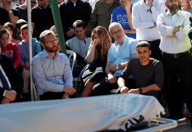 Relatives and friends mourn as they sit next to the body of Israeli rabbi Achiad Ettinger, wrapped in a Jewish prayer shawl, during his funeral, in the Jewish settlement of Eli in the Israeli-occupied West Bank March 18, 2019.