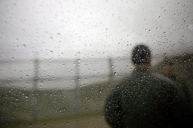 In this Jan 15, 2019 image, a U.S. Border Patrol agent looks towards a border wall as rain drops cover a window in San Diego. 