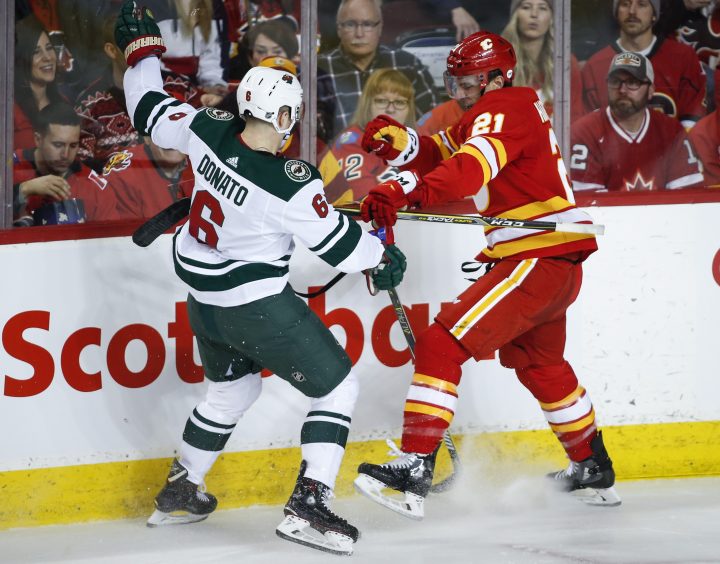 Minnesota Wild’s Ryan Donato, left, is checked by Calgary Flames’ Garnet Hathaway during first period NHL hockey action in Calgary, Saturday, March 2, 2019.
