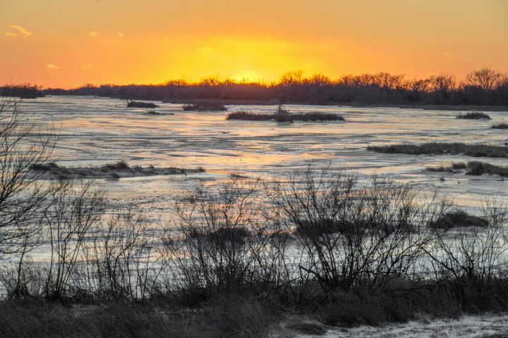 In this Feb. 7, 2019 photo, the sun sets behind the ice-covered Platte River in Columbus, Neb. Mentioning climate change can kill a conversation. But a new Alberta project is using the topic to start one - and has shown people from geologists to farmers to environmentalists they have more in common than they thought.