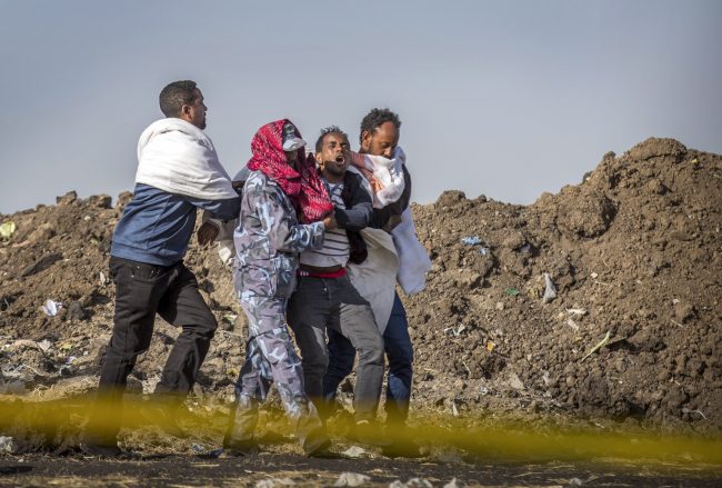 A grieving man who lost his wife is helped by a member of security forces and others at the site of the Ethiopian Airlines plane crash south of Addis Ababa, Ethiopia, March 13, 2019.