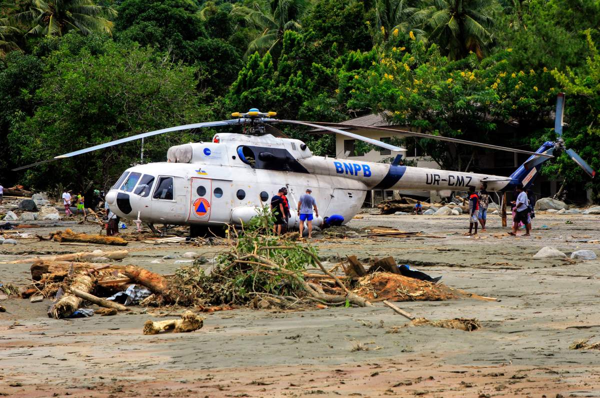 Residents stand next to a helicopter of the National Disaster Management Agency (BNPB) after the flash flood hit the area in Sentani, near Jayapura, Papua province, Indonesia, 17 March 2019.