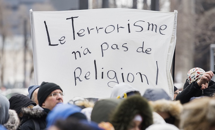 People hold up signs as they attend a vigil in Montreal, Sunday, March 17, 2019, following a shooting at a mosque in Christchurch, New Zealand which left 50 people dead and many more injured.
