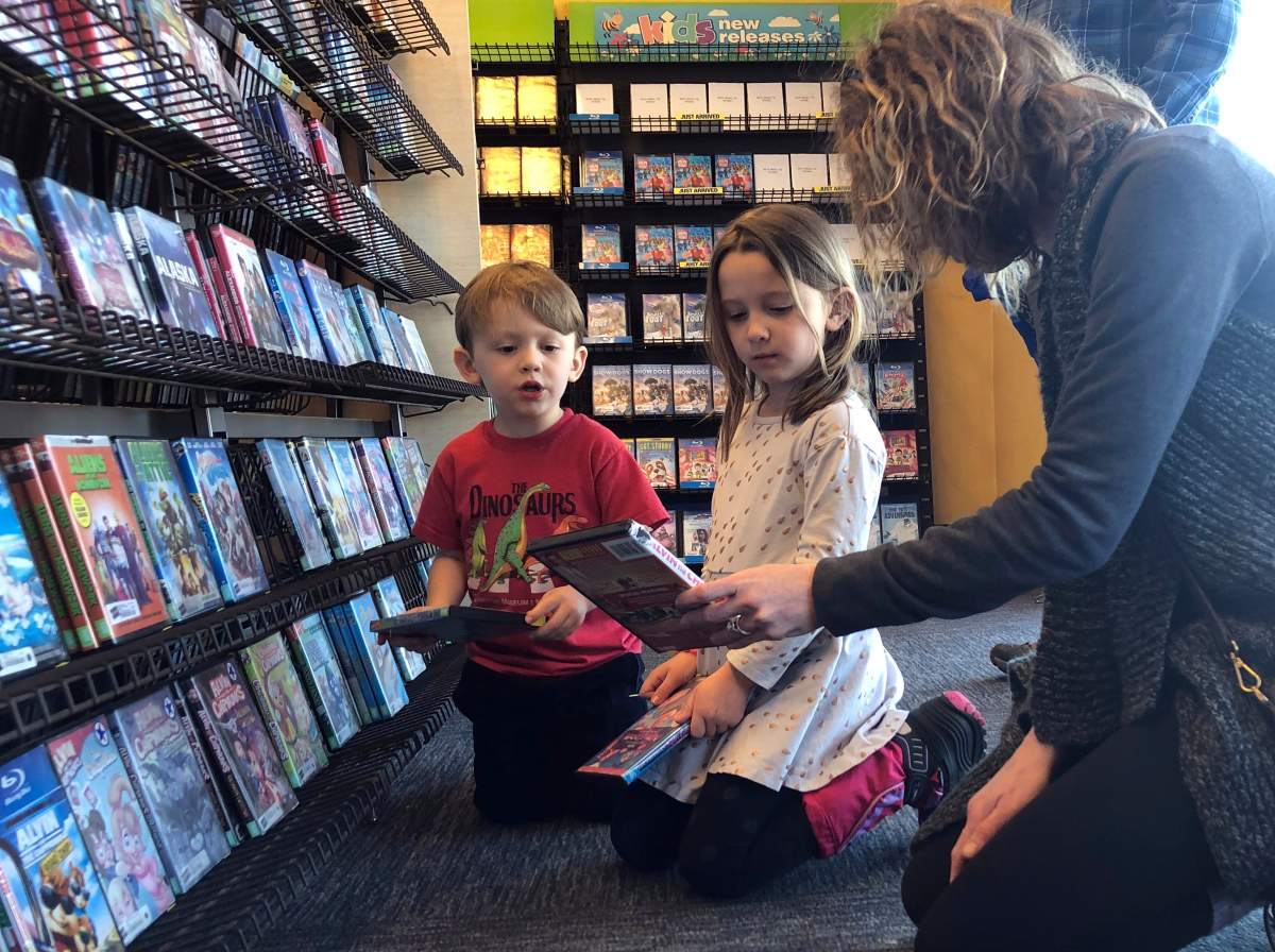 Elizabeth Gilless, of Memphis, Tenn., shows her children John, 3, and Ellen, 5, a movie from the children’s section at the last Blockbuster on the planet in Bend, Ore., on Tuesday, March 12, 2019. The family was vacationing in Oregon and stopped by the store to buy souvenirs on their way to Portland, Ore., after hearing it was the last Blockbuster on the planet.