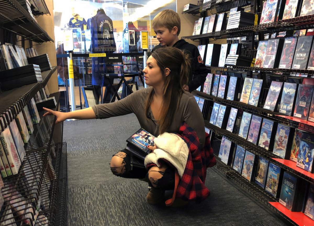 Tia Thiel and her son, Micah Knox, 7, browse a selection of movies at the last Blockbuster on the planet in Bend, Ore., on Monday, March 11, 2019. Thiel is a regular at the store and says she goes to the store for the older movies she can’t find on streaming services like Netflix.