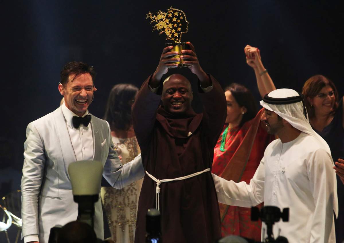Kenyan teacher Peter Tabichi, centre, actor Hugh Jackman, left, and Dubai crown prince Sheikh Hamdan bin Mohammed Al Maktoum, right, react after Tabichi won the $1 million Global Teacher Prize in Dubai, United Arab Emirates, Sunday, March 24, 2019. (AP Photo/Jon Gambrell)