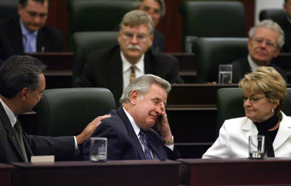 Alberta Premier Ralph Klein wipes away tears as his colleagues comfort him following a standing ovation at the end of his last day in the Alberta Legislature in Edmonton, Thursday, Aug. 31, 2006.