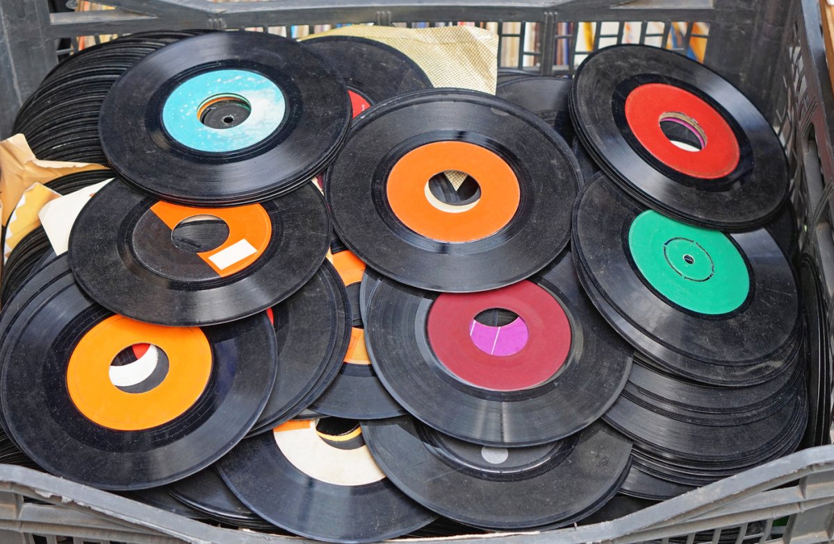 Second-hand vinyl records fill a basket at a flea market.