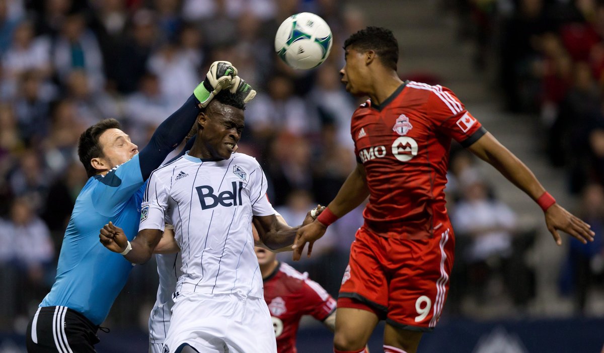 Vancouver Whitecaps goalkeeper Joe Cannon, left, punches the ball away from teammate Gershon Koffie, of Ghana, and Toronto FC's Emery Welshman, right, during the second half of an MLS soccer game in Vancouver, B.C., on Saturday March 2, 2013.