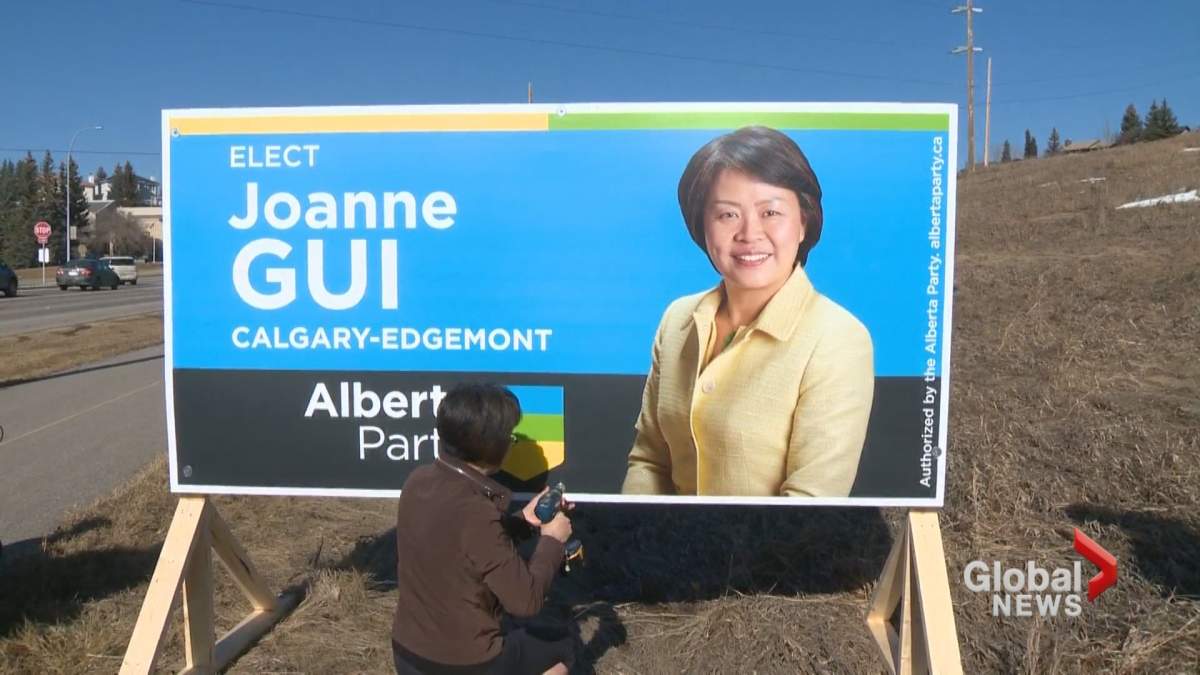 Joanne Gui installs a new election campaign sign in Calgary on Thursday, March 21.
