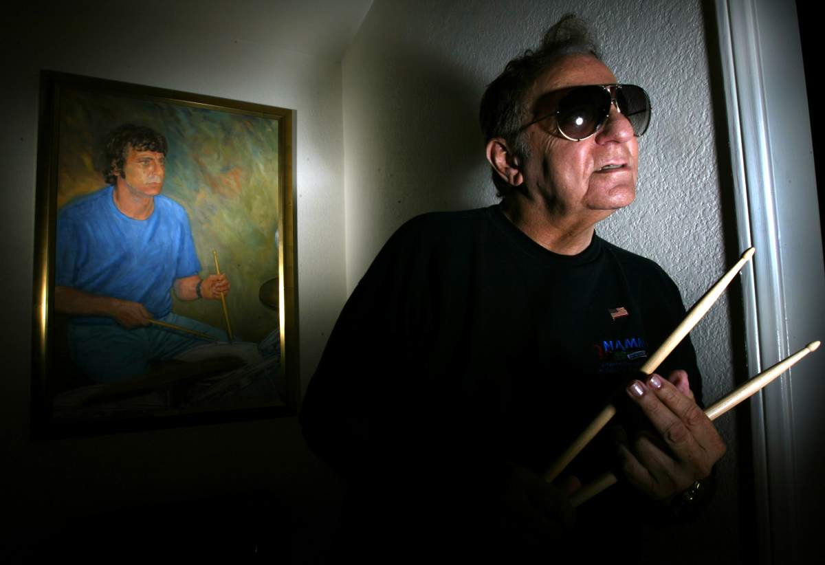Hal Blaine — one of the most famous drummers in the history of pop music, poses in front of an oil painting at his home in Palm Desert, Calif.