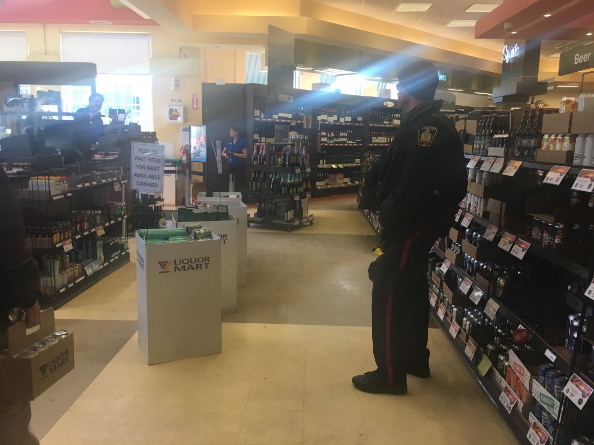 A fully uniformed police officer roams the Osborne Village Liquor Mart.
