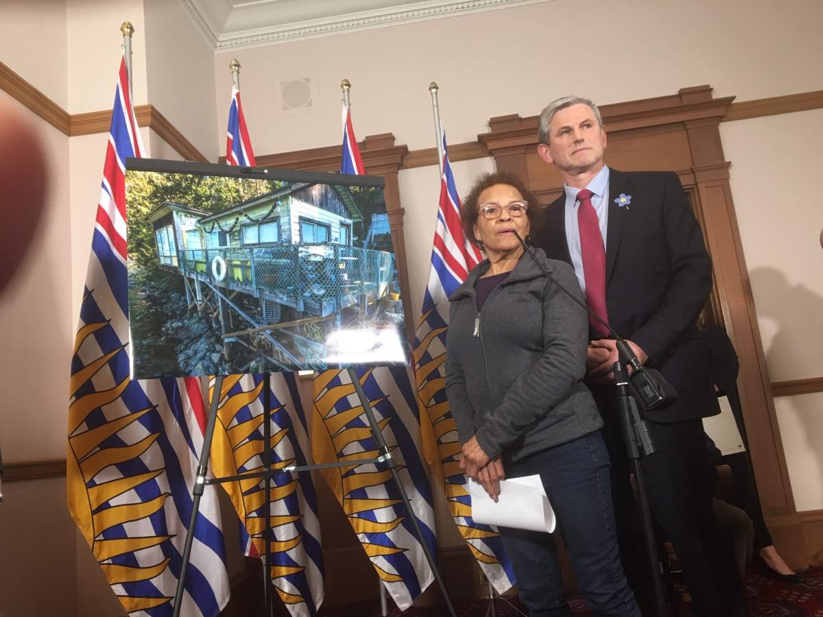 Belcarra property owner Charline Robson and Liberal leader Andrew Wilkinson standing beside a picture of Robson's summer cabin.