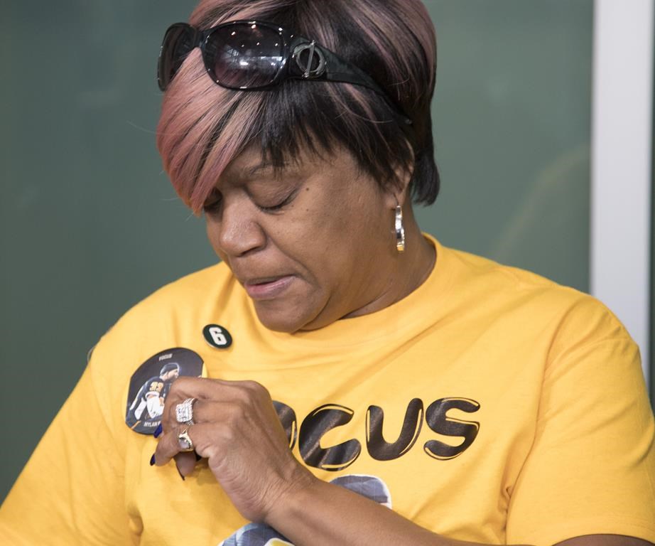Renee Hill, mother of Calgary Stampeders defensive back Mylan Hicks, toiches a phot of her son while wearing a t-shirt commemorating her son at the sentencing of his killer in Calgary, Alta., Monday, March 11, 2019.THE CANADIAN PRESS/Jeff McIntosh