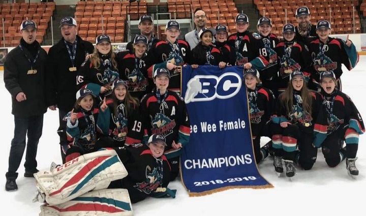Members of the Kelowna peewee girls hockey team surround their provincial championship banner after defeating Surrey in the gold-medal game.