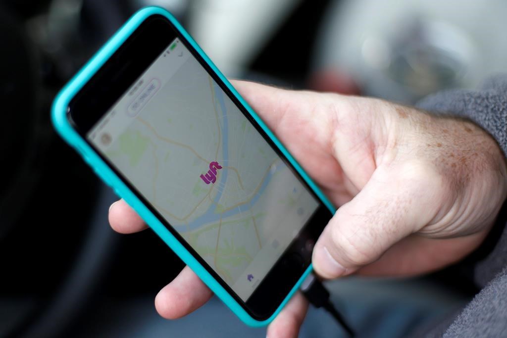 FILE- In this Jan. 31, 2018, file photo, a Lyft driver opens the Lyft app on his phone while waiting for a fare in Pittsburgh. Lyft is lifting the price target for its initial public offering in a sign of the excitement surrounding the stock market debut of a ride-hailing service that’s gaining ground on its rival Uber. With the revision disclosed Wednesday, March 27, 2019, Lyft is now seeking $70 to $72 per share, up from its previous goal of $62 to $68. (AP Photo/Gene J. Puskar, File)
