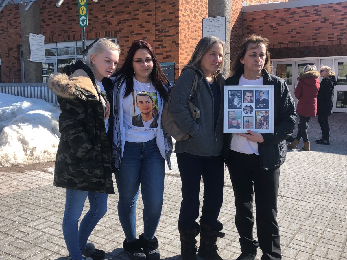 Denise Lane (right) is photographed outside the courthouse in Barrie, clutching a frame containing photos of her deceased son, Shawn Kelly. 
